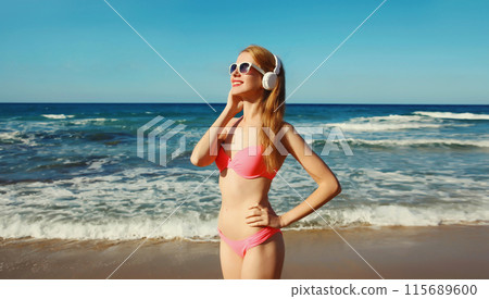 Summer vacation of relaxed happy young woman listening to music with headphones on the beach at sea Summer vacation of relaxed happy young woman listening to music with headphones on the beach at sea 115689600