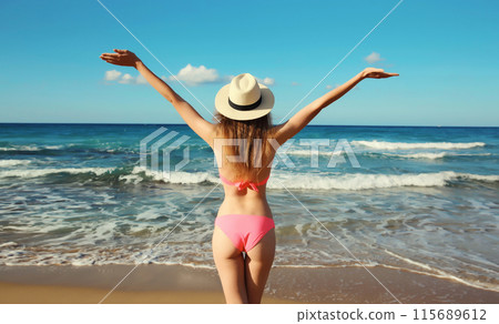 Summer vacation, beautiful happy woman in bikini swimsuit raising her hands up on the beach at sea 115689612