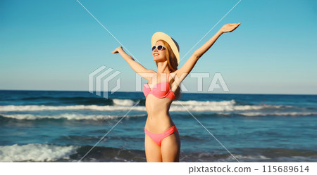 Summer vacation, happy joyful woman in bikini swimsuit, hat on the beach on sea coast with waves 115689614