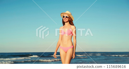 Summer vacation, beautiful happy slim woman in pink bikini swimsuit, tourist hat on the beach on sea 115689616