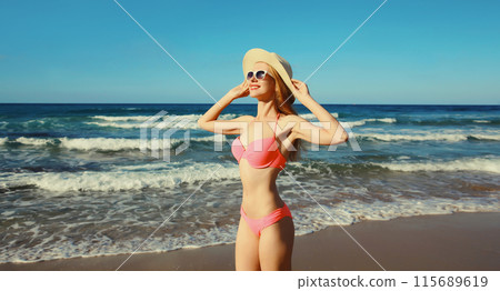 Summer vacation, beautiful happy slim woman in pink bikini swimsuit, tourist hat on the beach on sea 115689619