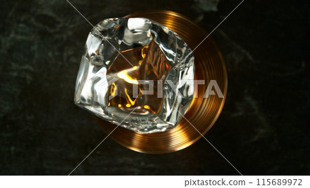 Closeup of ice cube falling into glass of whiskey. Closeup of ice cube falling into glass of whiskey. 115689972