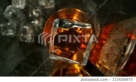 Closeup of ice cube falling into glass of whiskey. Closeup of ice cube falling into glass of whiskey. 115689975