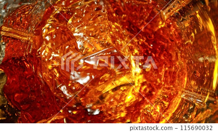 Closeup of ice cube inside glass of whiskey. 115690032