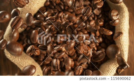 Freeze motion of flying coffee beans into jute sack. 115690062