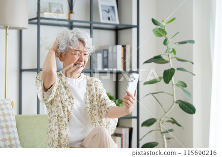 在客廳使用智慧型手機的高級女性 在客廳使用智慧型手機的高級女性 115690216
