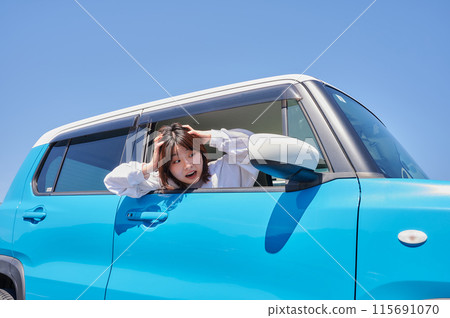 Woman sitting in a car and holding her head Woman sitting in a car and holding her head 115691070