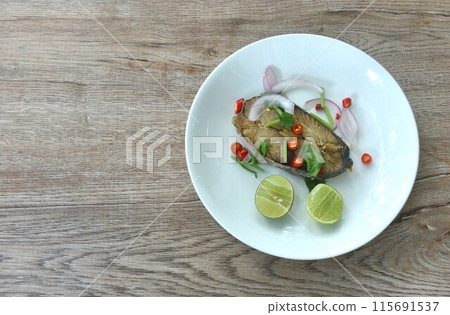 salty dry Indo-Pacific king mackerel fish topping chop shallot and chili with slice lemon salad on plate salty dry Indo-Pacific king mackerel fish topping chop shallot and chili with slice lemon salad on plate 115691537