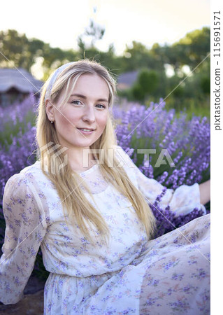 portrait of a young blonde woman in a pastel chiffon dress among lavender bushes portrait of a young blonde woman in a pastel chiffon dress among lavender bushes 115691571