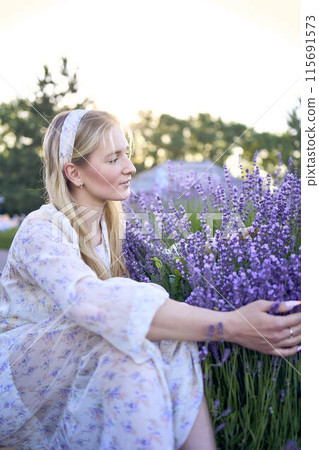 portrait of a young blonde woman in a pastel chiffon dress among lavender bushes portrait of a young blonde woman in a pastel chiffon dress among lavender bushes 115691573