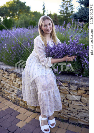 portrait of a young blonde woman in a pastel chiffon dress among lavender bushes 115691578