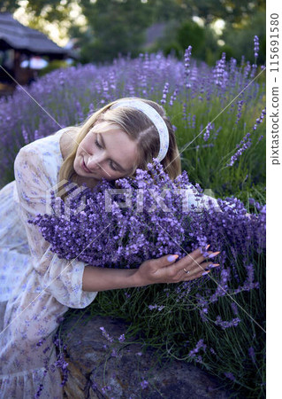 portrait of a young blonde woman in a pastel chiffon dress among lavender bushes portrait of a young blonde woman in a pastel chiffon dress among lavender bushes 115691580