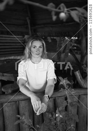 portrait of a young blonde girl in a yellow T-shirt and shorts in a wooden gazebo 115691628
