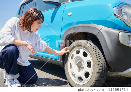Woman checking car tire flat air pressure Woman checking car tire flat air pressure 115691714