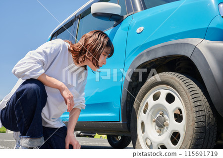 Woman checking car tire flat air pressure 115691719