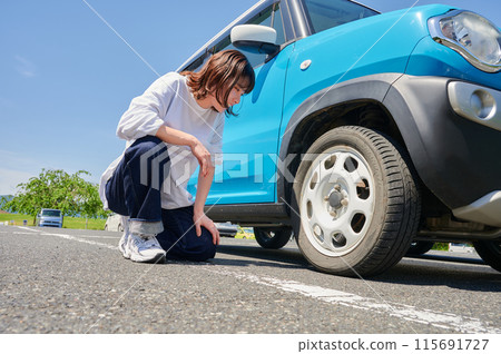 Woman checking car tire flat air pressure 115691727