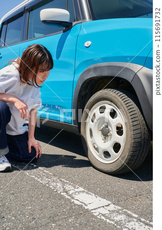 Woman checking car tire flat air pressure Woman checking car tire flat air pressure 115691732