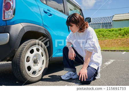 Woman checking car tire flat air pressure Woman checking car tire flat air pressure 115691733