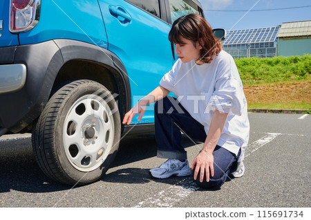 Woman checking car tire flat air pressure Woman checking car tire flat air pressure 115691734