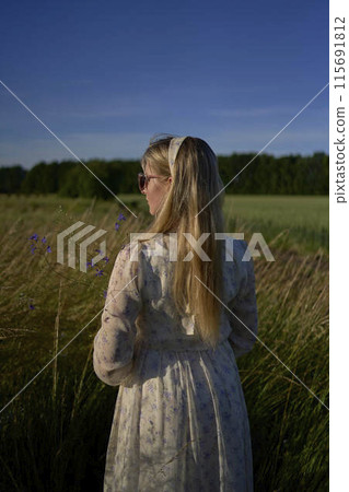 portrait of a young blonde woman in a pastel chiffon dress in a field of golden grass portrait of a young blonde woman in a pastel chiffon dress in a field of golden grass 115691812