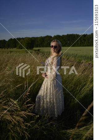 portrait of a young blonde woman in a pastel chiffon dress in a field of golden grass portrait of a young blonde woman in a pastel chiffon dress in a field of golden grass 115691813