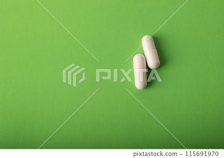Pills. Medical pills and capsules. Isolated on a green background. An allergy pill, antibiotics, supplements. Medicine, healthcare concept. Virus(viral) and flu diseases. High quality photo Pills. Medical pills and capsules. Isolated on a green background. An allergy pill, antibiotics, supplements. Medicine, healthcare concept. Virus(viral) and flu diseases. High quality photo 115691970