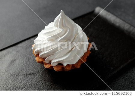 The sand basket is decorated with a high peak of protein cream. A tasty and sweet dessert stands on a black plate on a gray background The sand basket is decorated with a high peak of protein cream. A tasty and sweet dessert stands on a black plate on a gray background 115692103