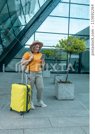 Happy traveling Caucasian woman in stylish casual clothes and hat uses mobile smartphone, checking trip destination on Internet. Female waiting at flight gates for plane boarding, smiling have a Happy traveling Caucasian woman in stylish casual clothes and hat uses mobile smartphone, checking trip destination on Internet. Female waiting at flight gates for plane boarding, smiling have a 115692264