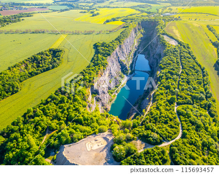 The breathtaking aerial view captures the lush green surroundings and turquoise waters of the abandoned Velka Amerika limestone quarry on a sunny summer day. Morina, near Prague, Czechia 115693457