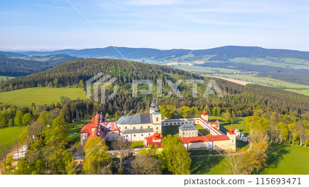 An aerial view of Hora Matky Bozi Monastery, located in Dolni Hedec near Kraliky, Czechia. The monastery is surrounded by lush greenery and a scenic landscape. An aerial view of Hora Matky Bozi Monastery, located in Dolni Hedec near Kraliky, Czechia. The monastery is surrounded by lush greenery and a scenic landscape. 115693471