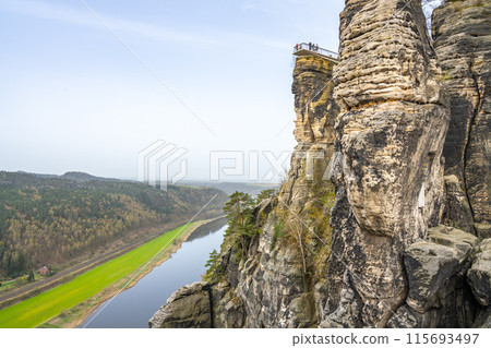 Overlooking the serpentine Elbe River, a visitor enjoys the vista from Bastei Bridge in Saxon Switzerland National Park. Kurort Rathen, Germany 115693497