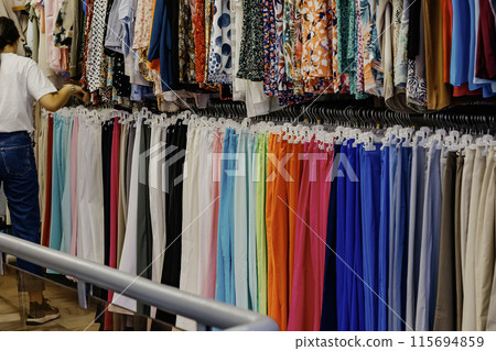 Woman Browsing Colorful samples of clothes Hanging In Store 115694859