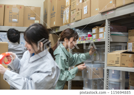 Three workers in work clothes checking and sorting inventory 115694885
