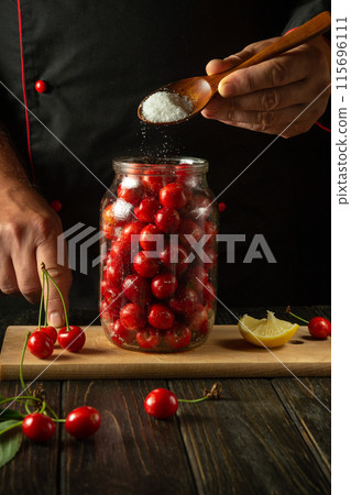 A chef spoons sugar into a jar of cherries before canning. The concept of making a delicious compote from sweet cherries. Advertising space A chef spoons sugar into a jar of cherries before canning. The concept of making a delicious compote from sweet cherries. Advertising space 115696111