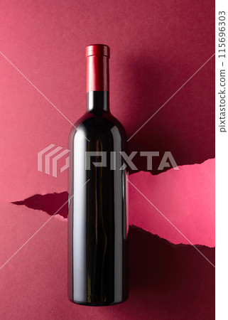 Bottle of red wine on a dark red background. Bottle of red wine on a dark red background. 115696303