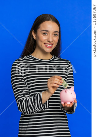 Happy rich woman puts money dollar pocket cash into piggy bank saving finance income growth salary 115697367