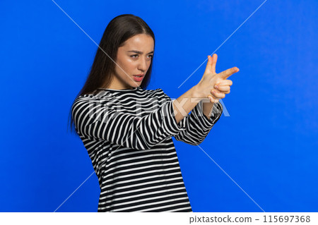Young woman pointing around with finger gun gesture making choice, shooting killing with hand pistol Young woman pointing around with finger gun gesture making choice, shooting killing with hand pistol 115697368