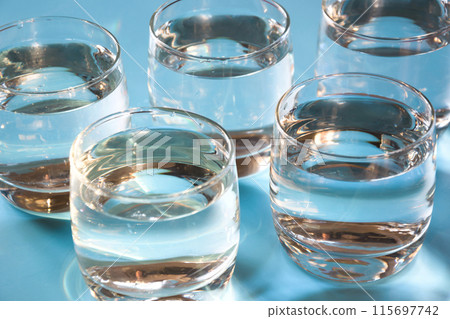 Glasses of water on pastel blue. Water balance for healthy. Pattern. Glasses of water on pastel blue. Water balance for healthy. Pattern. 115697742