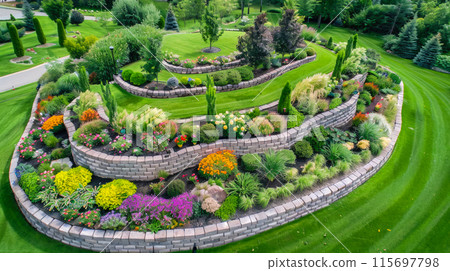 Landscaped home garden with terraces and rocks, beautiful design of luxury house back yard, stone retaining walls in summer. Concept of landscaping, backyard, plants, flower 115697798