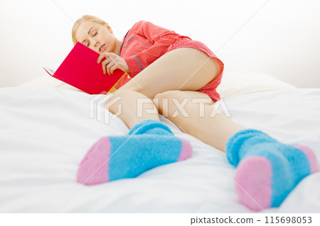 Woman relaxing in bed reading book Woman relaxing in bed reading book 115698053