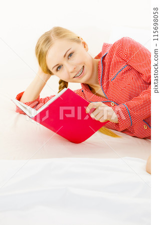 Woman relaxing in bed reading book Woman relaxing in bed reading book 115698058