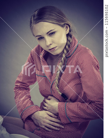 Sad young teenager woman on bed feeling pain 115698102
