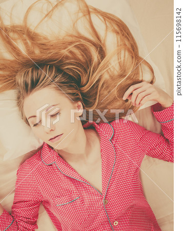 Young woman lying on bed wearing pajamas Young woman lying on bed wearing pajamas 115698142