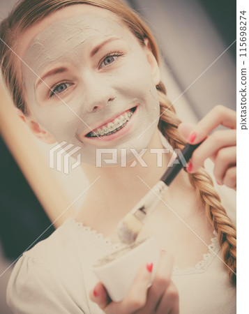 Woman applying with brush clay mud mask to her face Woman applying with brush clay mud mask to her face 115698274