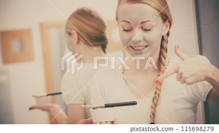 Woman applying with brush clay mud mask to her face Woman applying with brush clay mud mask to her face 115698279