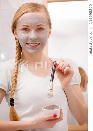 Woman applying with brush clay mud mask to her face 115698290