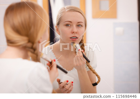 Young woman applying mud mask on face 115698446