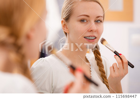 Woman applying with brush clay mud mask to her face Woman applying with brush clay mud mask to her face 115698447