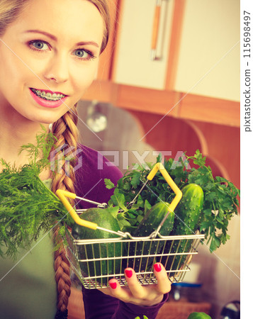 Woman in kitchen having vegetables holding shopping basket Woman in kitchen having vegetables holding shopping basket 115698497