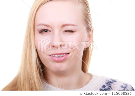 Happy woman showing her braces on teeth Happy woman showing her braces on teeth 115698525